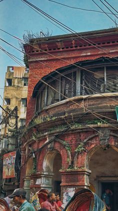 an old building with lots of wires above it and people standing outside the doorways