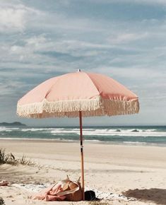 an umbrella is on the beach next to some towels and blankets in front of the ocean