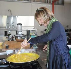 a woman cooking food in a large pan