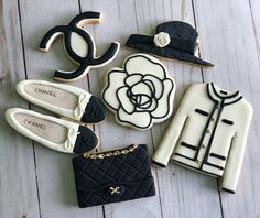 cookies decorated with black and white designs are on a wooden table next to purses