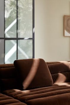 a brown couch sitting in front of a window