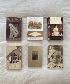 four books are laying on a bed with white sheets and one book is in the shape of a woman's torso