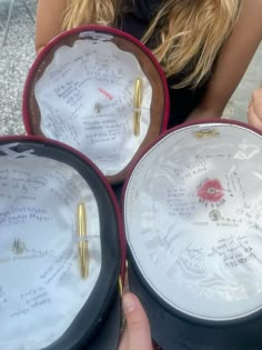 three hats with writing on them are being held by two women in front of the camera