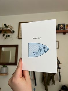 a person holding up a card with an image of a fish on it