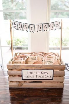 a wooden crate filled with lots of little bags sitting on top of a table next to a window