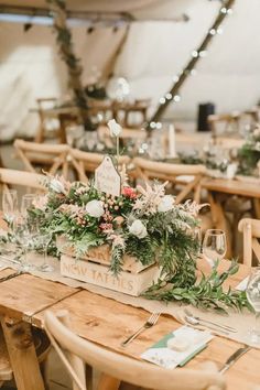 a wooden table topped with flowers and greenery