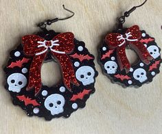 two pairs of earrings with skulls and bows on them