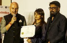 three people standing next to each other while holding an award plaque in front of them