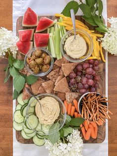 a platter filled with fruit, vegetables and dips