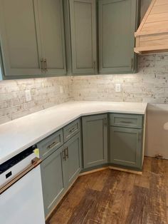 an empty kitchen with green cabinets and white counter tops, wood flooring in the foreground