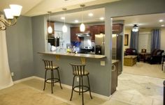 two bar stools sit in front of a kitchen counter with an open door leading to the living room