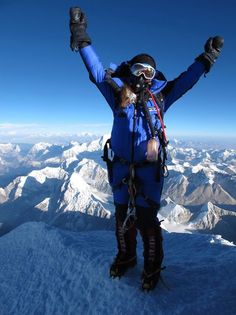 a man standing on top of a snow covered mountain with his arms in the air