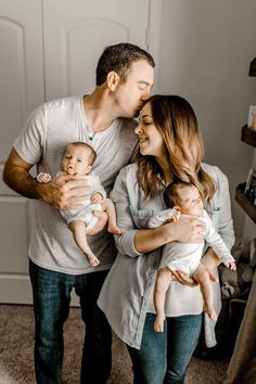 a man and woman holding two babys in their arms