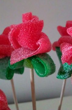 three cake pops decorated with pink flowers and green leaves