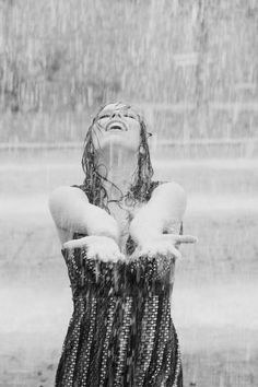 a woman is standing in the rain with her hands on her hips and eyes closed