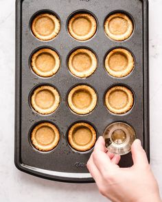 a person is placing mini pies in a muffin tin