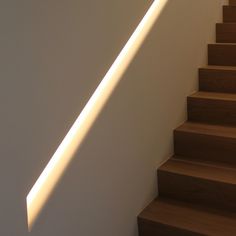 the light is shining down on some stairs and wood steps with white walls in the background