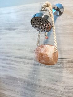 a shower head with soapy water running down it's side and a rope attached to the faucet