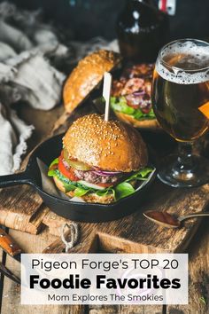 two large burgers sitting on top of a pan next to a glass of beer