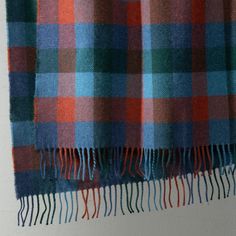 an orange, blue and green plaid blanket hanging on a wall