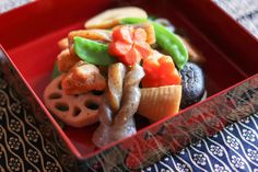 a red box filled with assorted veggies on top of a blue and white table cloth