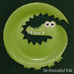 a green paper plate with an image of a crocodile's head and teeth on it