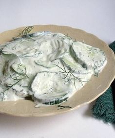 a white plate topped with cucumber and cream sauce