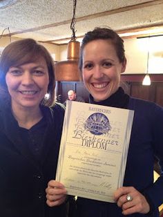 two women standing next to each other holding up a paper with an award on it