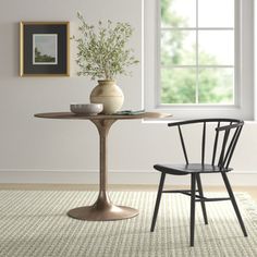 a small table with two chairs and a vase on it in front of a window