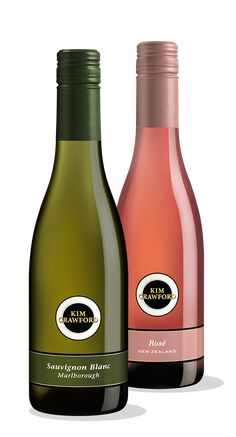 two bottles of wine sitting next to each other on a white surface, one is green and the other is pink