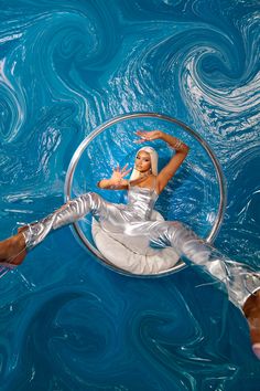 a woman floating in the water on top of a metal circle with her legs spread out