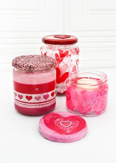 jars filled with candles and hearts on top of a white table next to each other