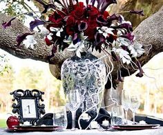 a vase filled with flowers sitting on top of a table next to glasses and an empty plate