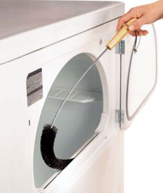 a person using a brush to clean an appliance in a white washer