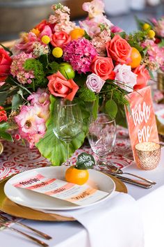 the table is set with oranges and pink flowers