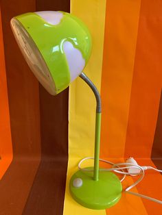 a green lamp sitting on top of a table next to a yellow and orange wall