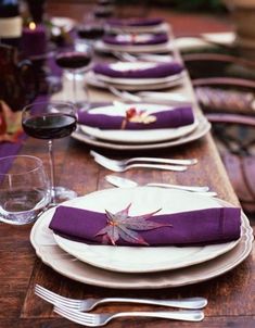 the table is set with purple napkins and place settings