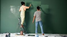 two people are painting the walls in a room that is being remodeled with green paint