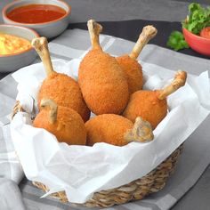 some food is sitting in a basket on a table next to bowls and sauces