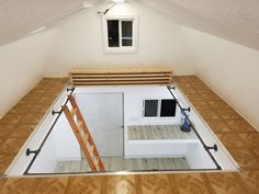 an aerial view of a loft with wood flooring and white walls, looking down into the attic