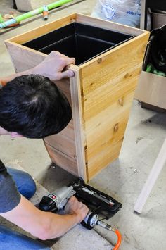 a man working on a wooden cabinet in a shop