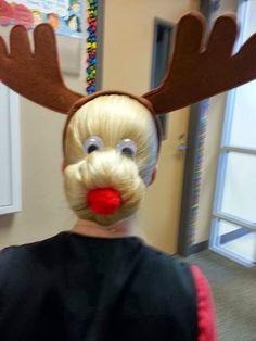 a woman with blonde hair and reindeer antlers on her head in an office cubicle