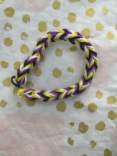 a purple, yellow and white braided bracelet sitting on top of a polka dot tablecloth