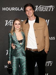 two people standing next to each other on a red carpet