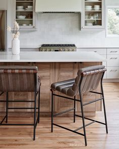 two leather chairs sitting in front of a kitchen island