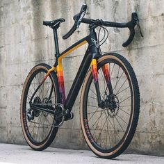 a bike leaning against a wall on the side of a building with orange, yellow and red stripes