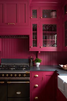 a kitchen with red painted cabinets and black counter tops, along with a white sink