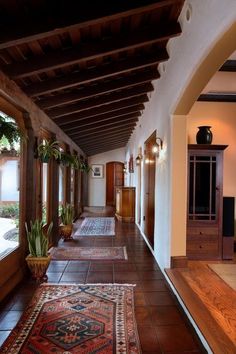 a long hallway with lots of windows and rugs on the floor next to it