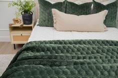 a bed with green bedspread and pillows