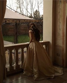 a woman in a dress standing on a balcony